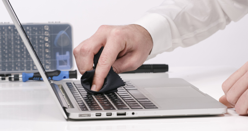 Männerhand reinigt Tastatur eines Laptops